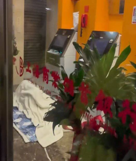 有人霸占台北市信义路四段上海商银松南分行的自动柜员机服务区,反锁玻璃门铺上被褥盖著棉被呼呼大睡,引起网友热议。(图撷取自网路影片) 有人霸占台北市信义路四段上海商银松南分行的自动柜员机服务区,反锁玻璃门铺上被褥盖著棉被呼呼大睡,引起网友热议。(图撷取自网路影片)
