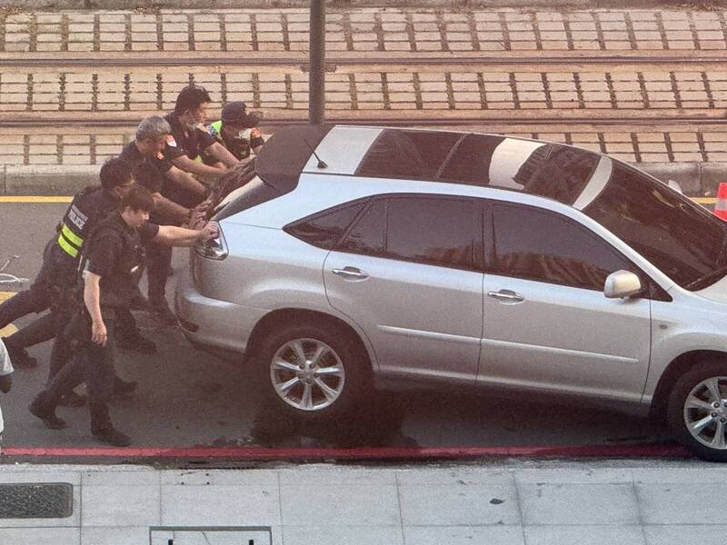 高雄轿车不明原因撞断轻轨号志,警察协助把肇事车推离道路上,避免影响交通。(民众提供) 高雄轿车不明原因撞断轻轨号志,警察协助把肇事车推离道路上,避免影响交通。(民众提供)