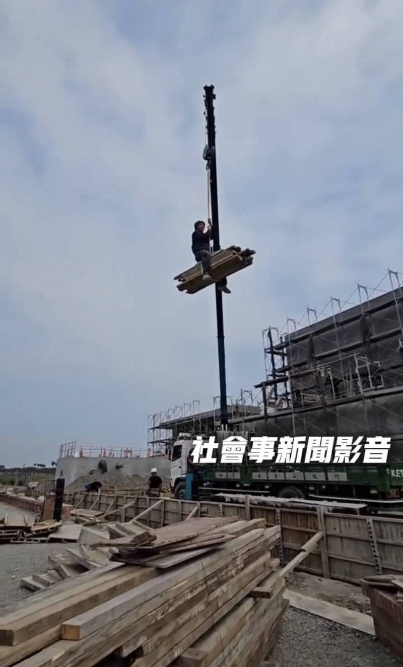 工人坐在模板上随吊车垂降到地面，令人捏把冷汗。（取自「社会事新闻影音」）