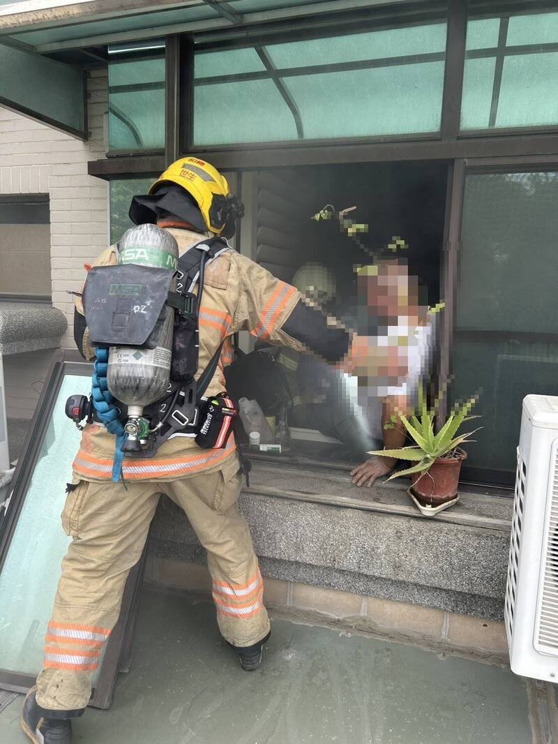 消防人员架梯进入台南北区育德一街的失火民宅二楼，将受困二楼房内的八十岁老翁移到二楼户外阳台。（民众提供）
