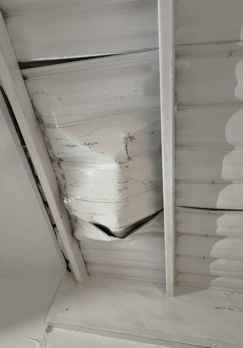 新北市板桥一处社区保全员竟跑到顶楼往楼下丢掷灭火器，造成隔壁社区铁皮屋顶毁损。（记者吴仁捷翻摄）