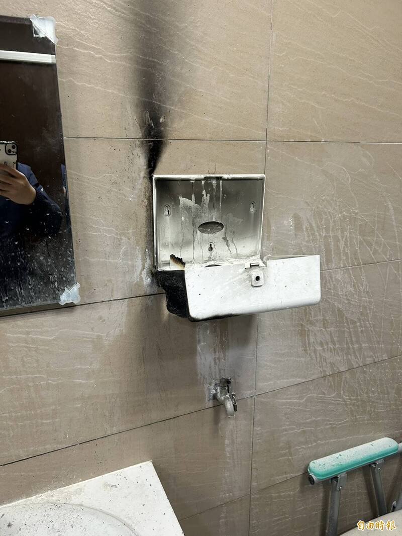 新店慈济女厕洗手台旁的擦手纸架遭人点火毁损。（记者郑景议翻摄）