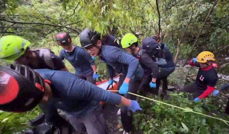 台北一支登山团，昨天攀爬和平区蝴蝶谷瀑布步道遇上落石，造成2男2女不幸丧名，搜救人员接力将遗体运送下山。（记者陈建志翻摄）