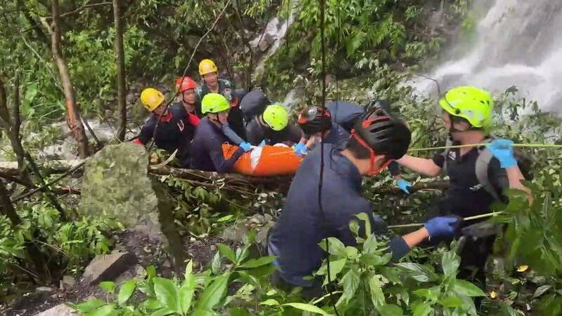 台北一支登山团，昨天攀爬和平区蝴蝶谷瀑布步道遇上落石，造成2男2女不幸丧名，搜救人员在瀑布激流旁冒险将遗体运送下山。（记者陈建志翻摄）