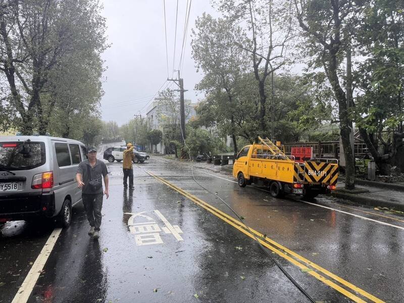 蔷琵台风来势汹汹。基隆市七堵区八堵路一处电线上午强风吹落，警方获报通知台电人员协助剪断电线后，徒手将缠绕车子的电线拉出，协助车主脱困。（警方提供）