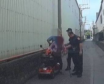 员警与热心骑士合力将电动代步车推到安全处。（记者许国桢翻摄）